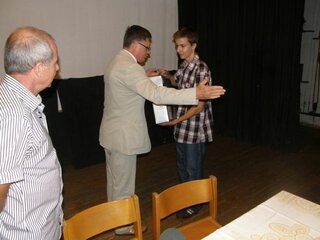 Riaditeľ školy odovzdáva cenu - notebook  za súťaž Mladý priemyslovák žiakovi 1.B triedy Michalovi Vančíkovi